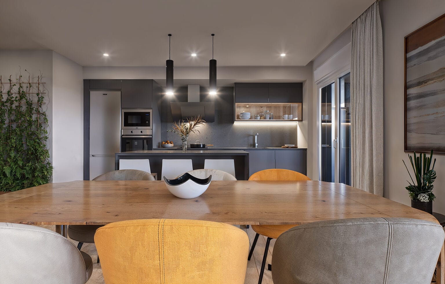 Salón con mesa de comedor y cocina al fondo en vivienda Minuetto Zaragoza